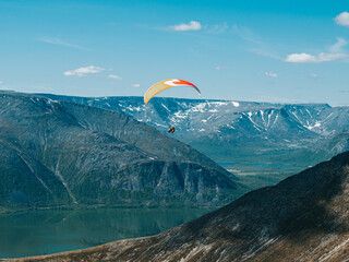 Extreme sportsman flies a paraglider against the background of  mountains and lake. Russia, Khibiny Mountains,  Kirovsk
