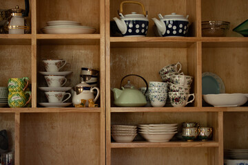 Ceramic crockery and bowls arranged in a cabinet for home decoration.
