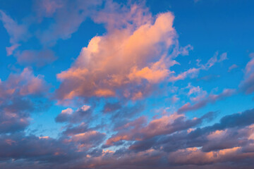 Naklejka na ściany i meble Blue sky background. Blue sky with pink clouds. Natural texture. A pattern with a clear daylight sky. Summer clouds bottom view. Background natural. Texture with blue firmament.