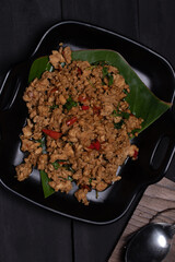 Stir-fried basil with chicken and steamed rice on black background
