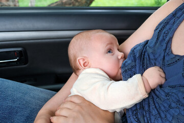Mother breastfeeding child in a car, public breastfeeding. Mom holding adorable newborn baby in auto. Young Woman sitting in the car and nursing infant. Concept of modern motherhood