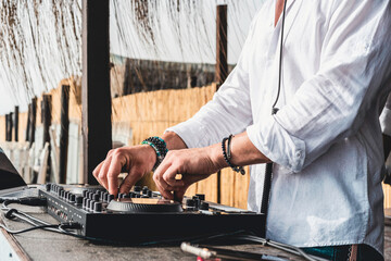 Disc jockey playing music for tourist people at club party outdoors on the beach - Dj at music live event - Live event, music and fun concept - Entertainment and party concept - Focus on hands