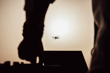 Silhouette of drone pilot flying with quadcopter outdoors at sunset - Drone pilot flying and...