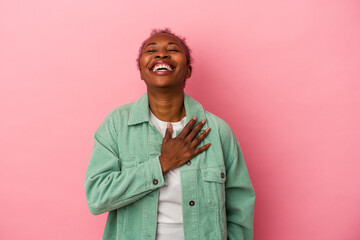 Young african american woman isolated on pink background laughs out loudly keeping hand on chest.