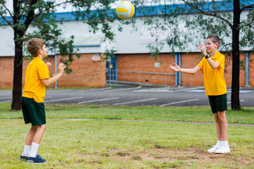 Two Aussie school boys throwing a ball together outside