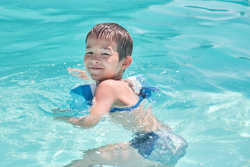Fototapeta na wymiar Little asian boy is learning to swim in outdoor pool