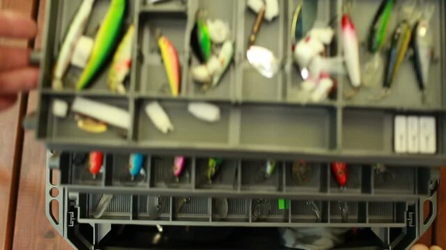 man opens a fishing box with baits first-person view close-up
