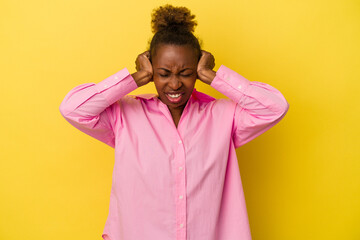 Young african american woman isolated on yellow background covering ears with hands.