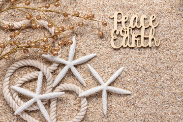 beach or tropical theme holiday greeting with glittery balls on twigs, white starfish, nautical rope, and Peace on Earth on beach sand all in natural tones