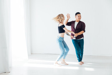 a man and a woman dance bachata music in a white room
