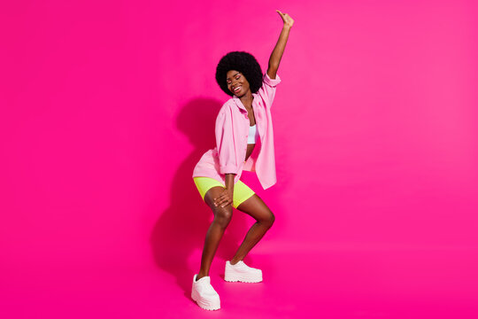 Photo of pretty charming dark skin lady wear casual shirt dancing twerk smiling isolated pink color background