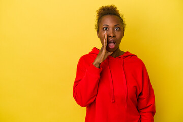 Young african american woman isolated on yellow background shouts loud, keeps eyes opened and hands tense.