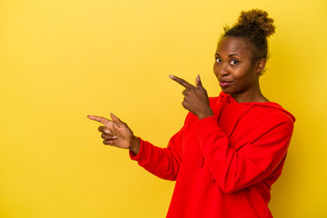 Young african american woman isolated on yellow background pointing with forefingers to a copy space, expressing excitement and desire.