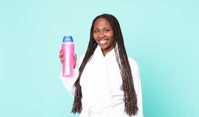 black african american adult woman wearing bathrobe and holding a shampoo