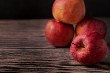 Red apples on dark wooden background, closeup shot, low key, copy space for designers