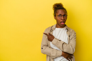 Obraz premium Young african american woman isolated on yellow background pointing to the side