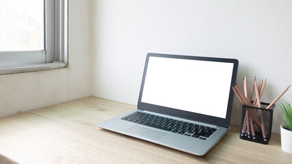 Laptop computer with white blank screen on wood desk. Workspace, workplace, desktop office concept.