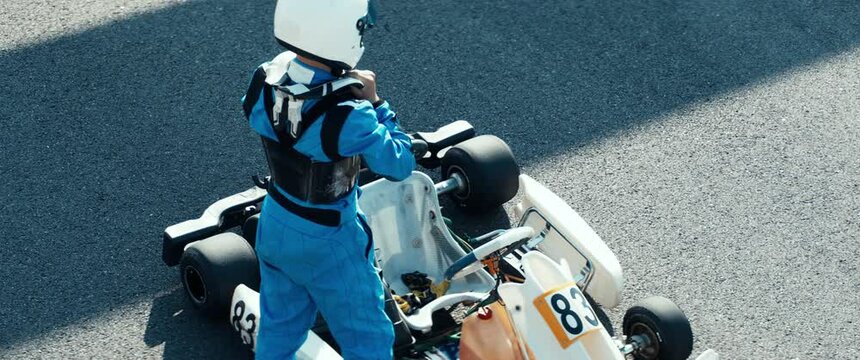 Teenager professional karting racer putting on protective gear on a race track. Shot with 2x anamorphic lens