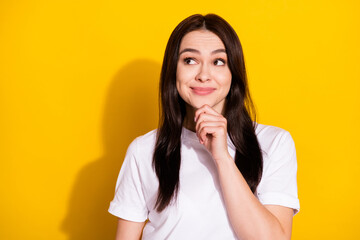 Photo of thoughtful adorable young woman wear white t-shirt smiling arm chin looking empty space isolated yellow color background