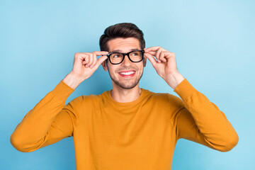 Photo of young cheerful man happy positive smile hands touch glasses look empty space isolated over blue color background