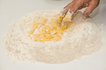 Flour and eggs. Hands kneading dough on board - flour and eggs. Selective focus. The concept of cooking, alibi, pizza with your own hands