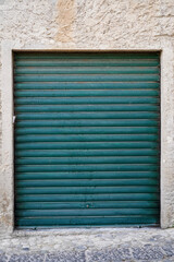 green garage, store shutter door in stone wall