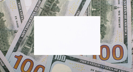 Against the background of American dollars, a white blank card with a place to insert text. Template. Financial concept