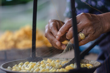 Woman Reeling The Thread, a part for making silk in Thailand.