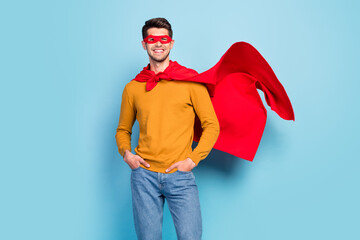 Photo of young superman happy positive smile hands in pocket power strong isolated over blue color...