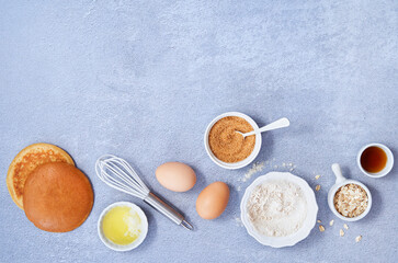 Fototapeta na wymiar Banner food background. Ingredients for homemade oat pancake with whole grain oat, coconut sugar, vanilla syrup, organic eggs on light blue background. Healthy food recipe. Top view. Copy Space.