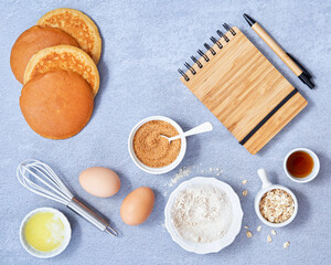 Food background. Ingredients for homemade oat pancake with whole grain oat, coconut sugar, vanilla syrup, organic eggs on light blue background. Healthy food recipe. Top view. Copy Space.