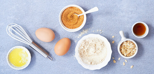 Ingredients for homemade oat pancake with whole grain oat, coconut sugar, vanilla syrup, organic eggs on light blue background. Healthy food recipe photography. Top view. Copy Space.