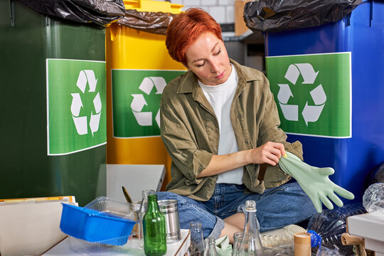 Woman is going to sort garbage, wearing gloves. Redhead eco-friendly female separate waste and throwing trash into recycling bins. Ecology lifestyle. environmental segregation, copy space
