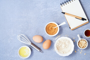 Healthy Food Background, Ingredients for homemade oat pancake with whole grain oat, coconut sugar, vanilla syrup, organic eggs next to a white notebook in a pen on light blue background. Copy space.