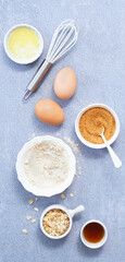 Food background banner, Ingredients with whole grain oat, coconut sugar, vanilla syrup, organic eggs on light blue background. Healthy recipe concept. Top view. Copy Space.