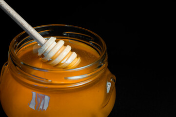 fresh honey is poured into a transparent jar on a black background. High quality photo