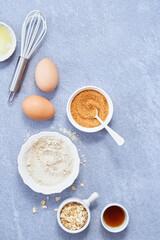 Food background, Ingredients for homemade oat pancakes with whole grain oat, coconut sugar, vanilla syrup, organic eggs on light blue background. Healthy recipe concept. Top view. Copy Space.