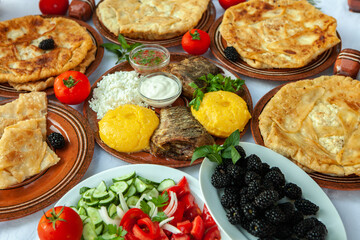 Homemade Romanian Food with grilled fish, polenta, pies, vegetables with red wine. Platter on camping.