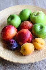 Fototapeta na wymiar Wooden bowl with various colorful fruit. Selective focus.