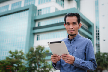 Asian man holding a tablet on the office building background