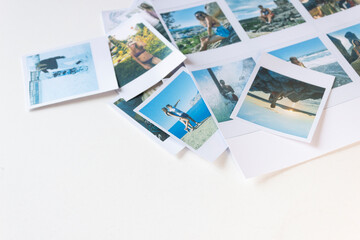 Printed and cut-out photos on a white background. There are a lot of polaroid photos on the table.