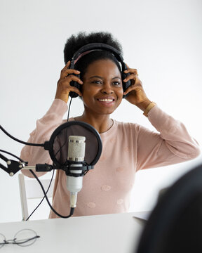 African American Woman With Headphones And A Microphone Recording A Podcast In A Recording Studio, Millennial Black Woman Creating Audio Content, Confident Woman Working In Radio Or Interviewing