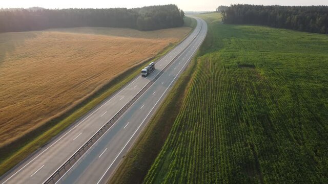 Aerial drone footage: Large car transporter (car hauler) delivery truck is fully loaded on the highway. Transportation of new cars from the factory to the car dealership.