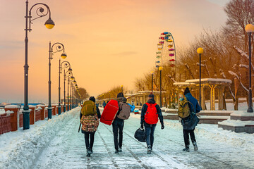 Four backpackers walk along the embankment in winter in Vladivostok, Russia
