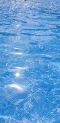 Pure blue water in the swimming pool with light reflections. Top view aerial. Vertical