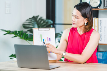 Asian businesswoman presenting business report via video call on a laptop at home. Businessperson or entrepreneur working, online shopping, e-commerce, internet banking, working from home concept