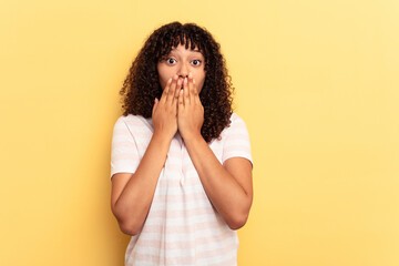 Young mixed race woman isolated on yellow background shocked, covering mouth with hands, anxious to discover something new.