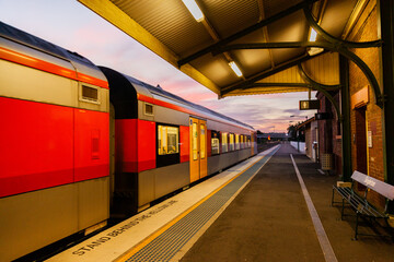Passenger train pulling away from deserted country railway station