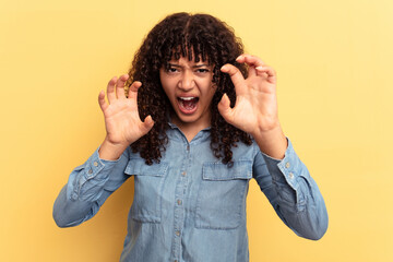 Young mixed race woman isolated on yellow background upset screaming with tense hands.