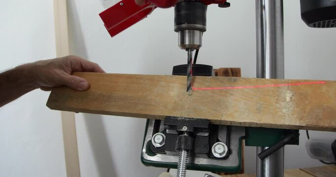 DIY Woodworking, Man Drilling Sharp Angle Hole In Wood Plank Using Benchtop Drill Press